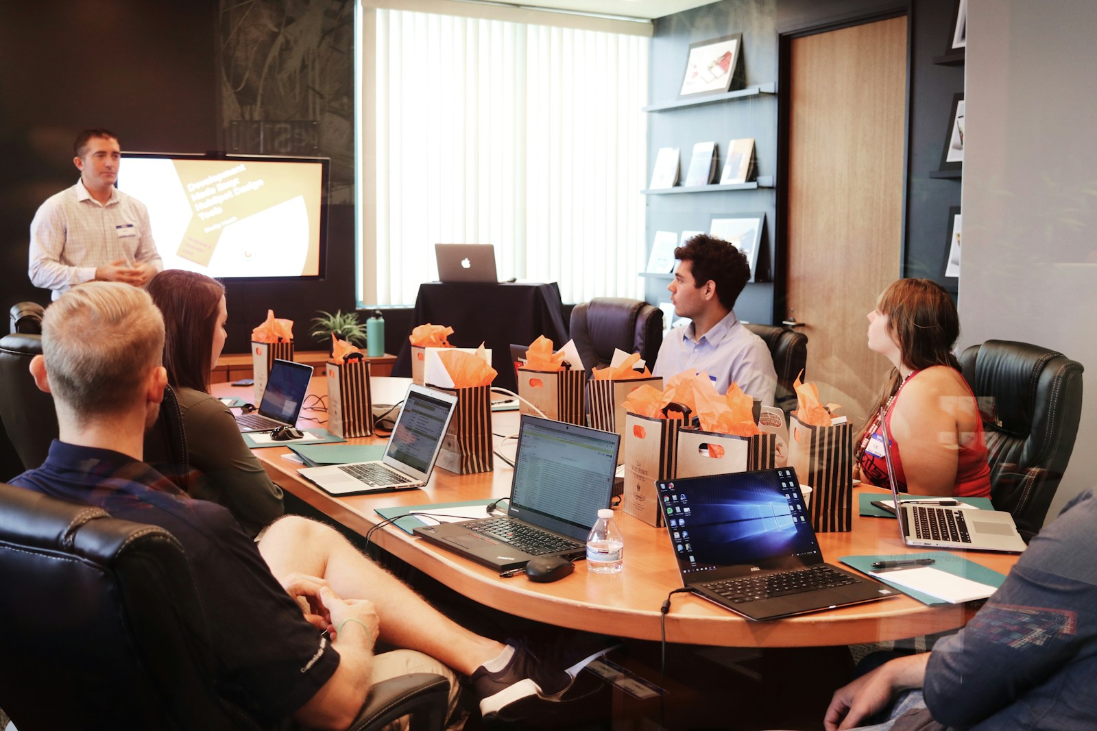 man standing in front of people sitting beside table with laptop computers business